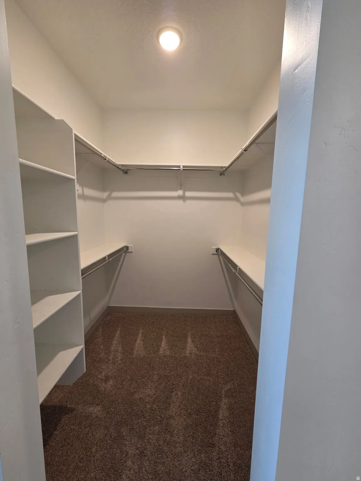 Walk-in closet with integrated shelving, ample hanging rods, and recessed lighting