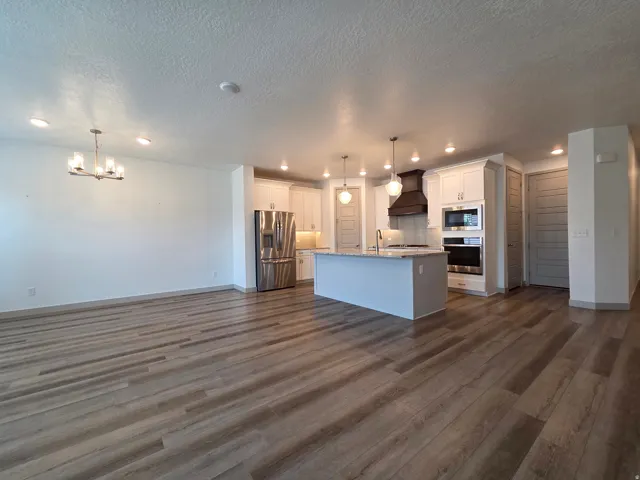 Open-concept living space with wood-finish flooring, recessed lighting, and a chandelier fixture