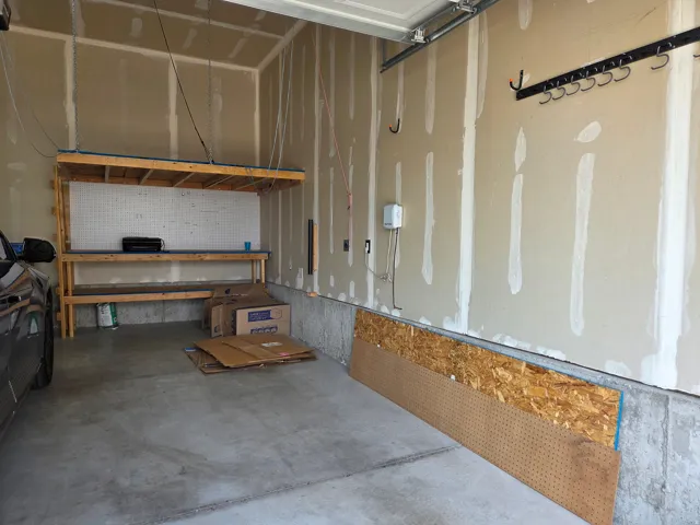 Concrete flooring with built-in workbench featuring shelving and pegboard