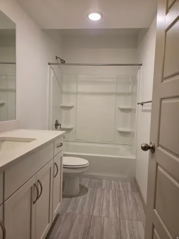 White vanity with an integrated sink, polished chrome hardware, and a solid surface countertop