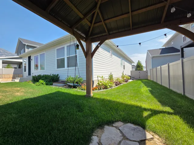 Expansive backyard featuring a manicured lawn, established landscaping, and a privacy fence