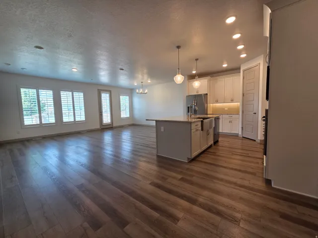 Open-concept living area with wood-finish flooring, recessed lighting, and white plantation shutters