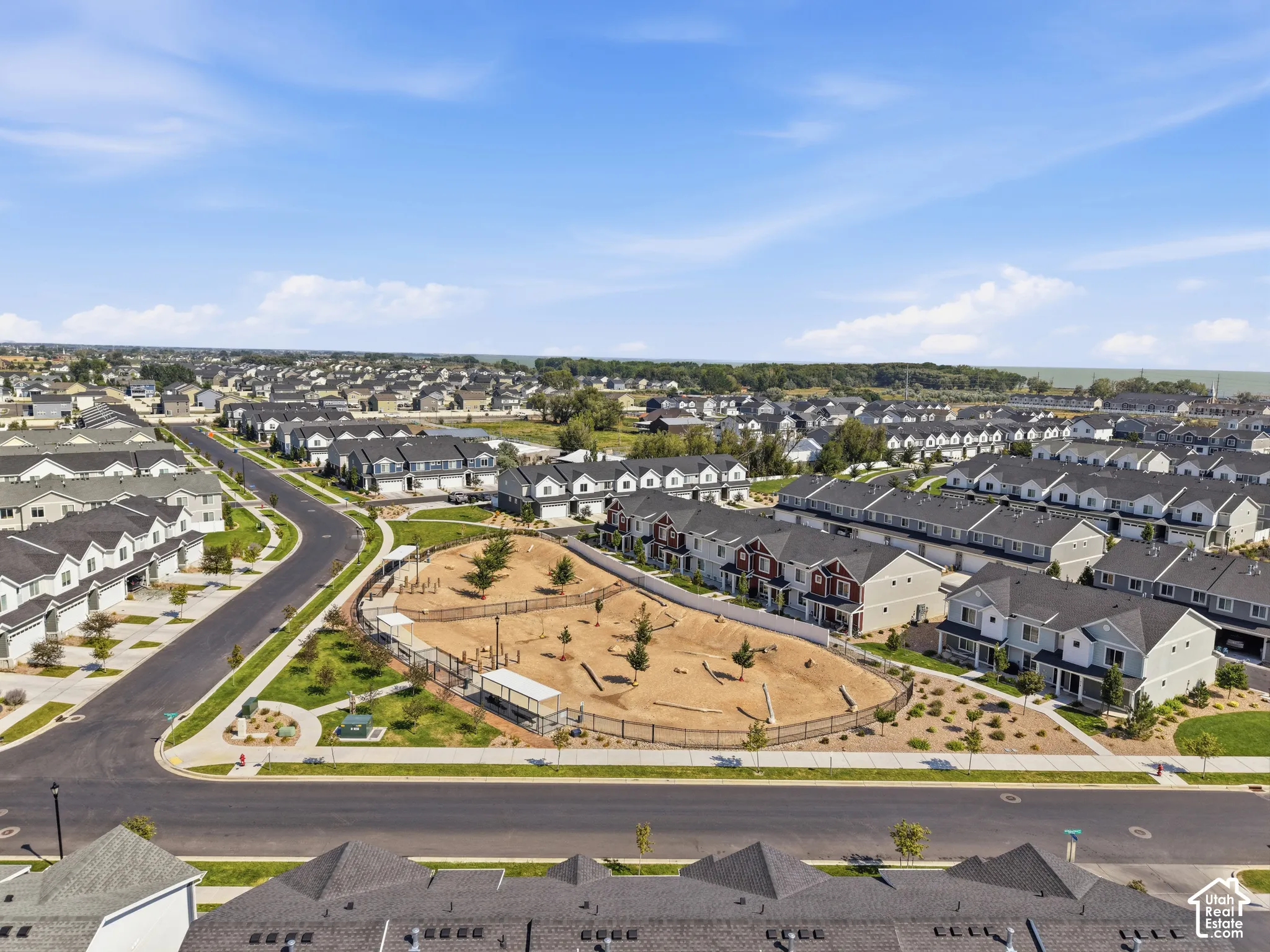 Aerial community overview featuring a central park area, tree-lined streets, and numerous residential properties with varied exteriors