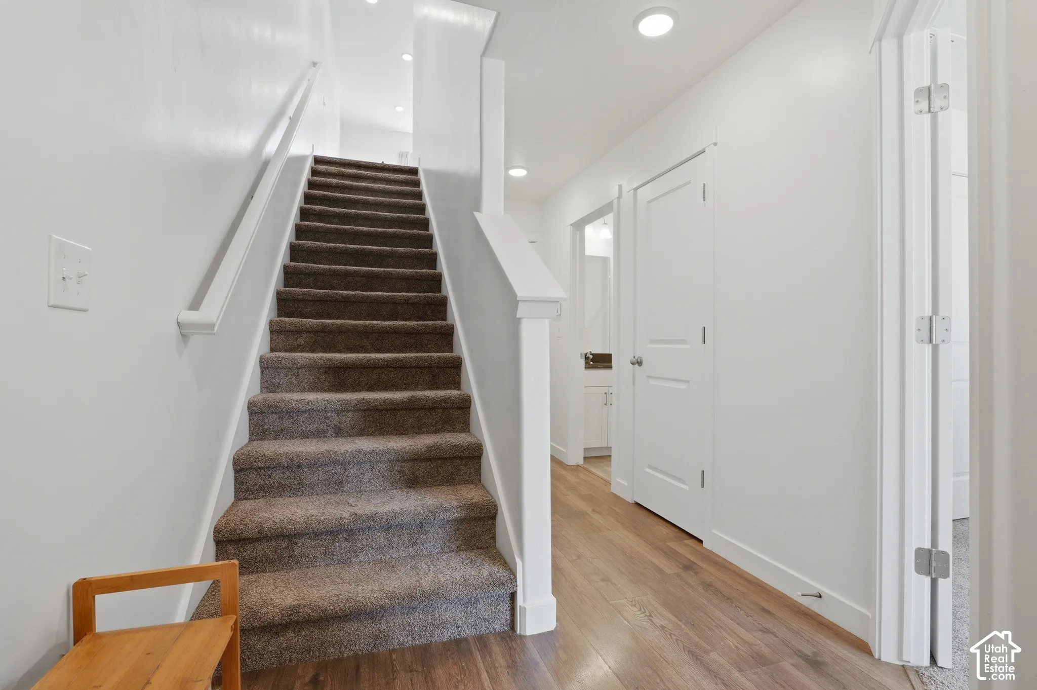 Bright hallway with wide staircase featuring carpeted treads and white painted railings