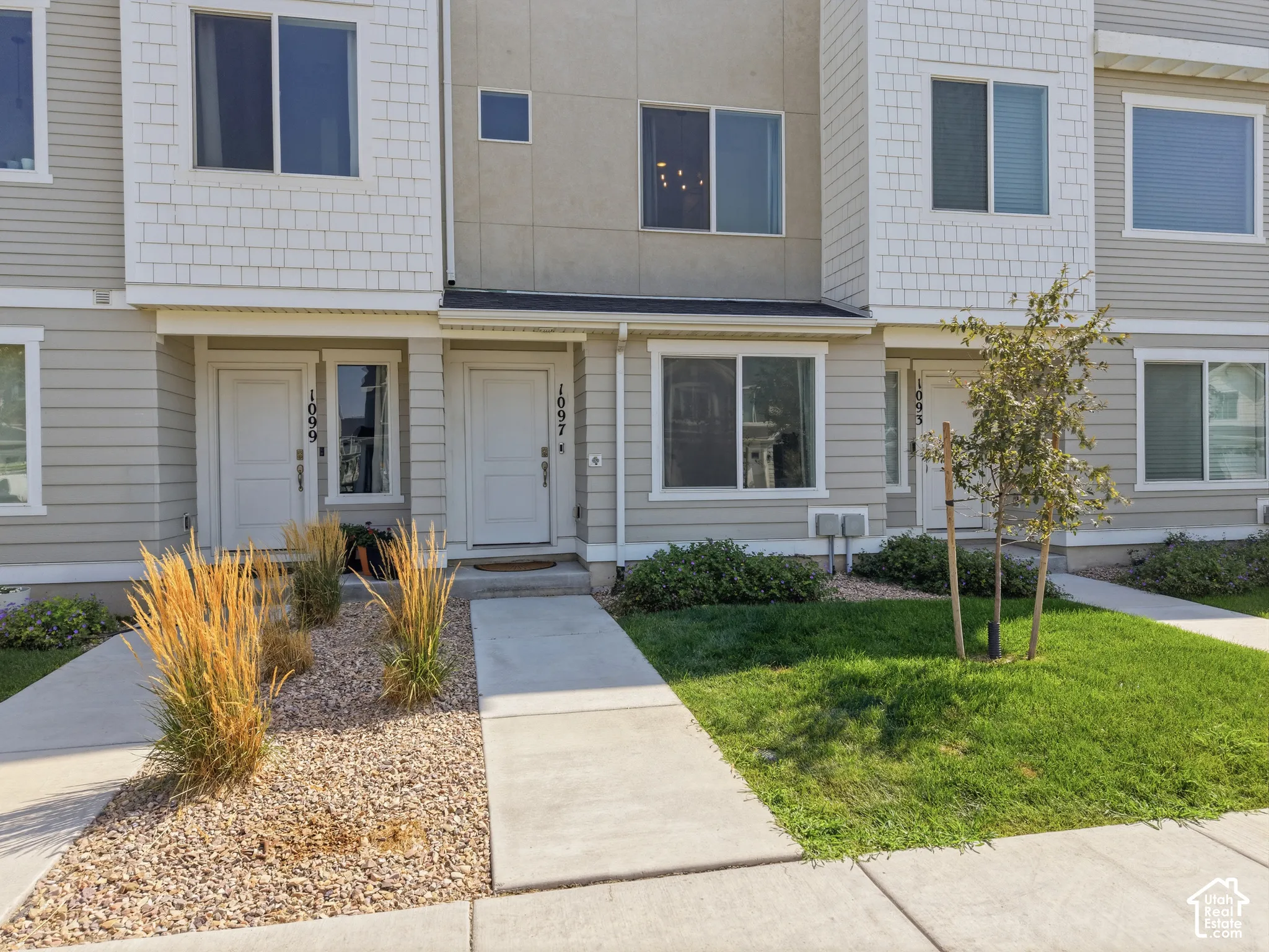 Multi-level townhome exterior featuring light-toned siding, white trim, and multiple windows