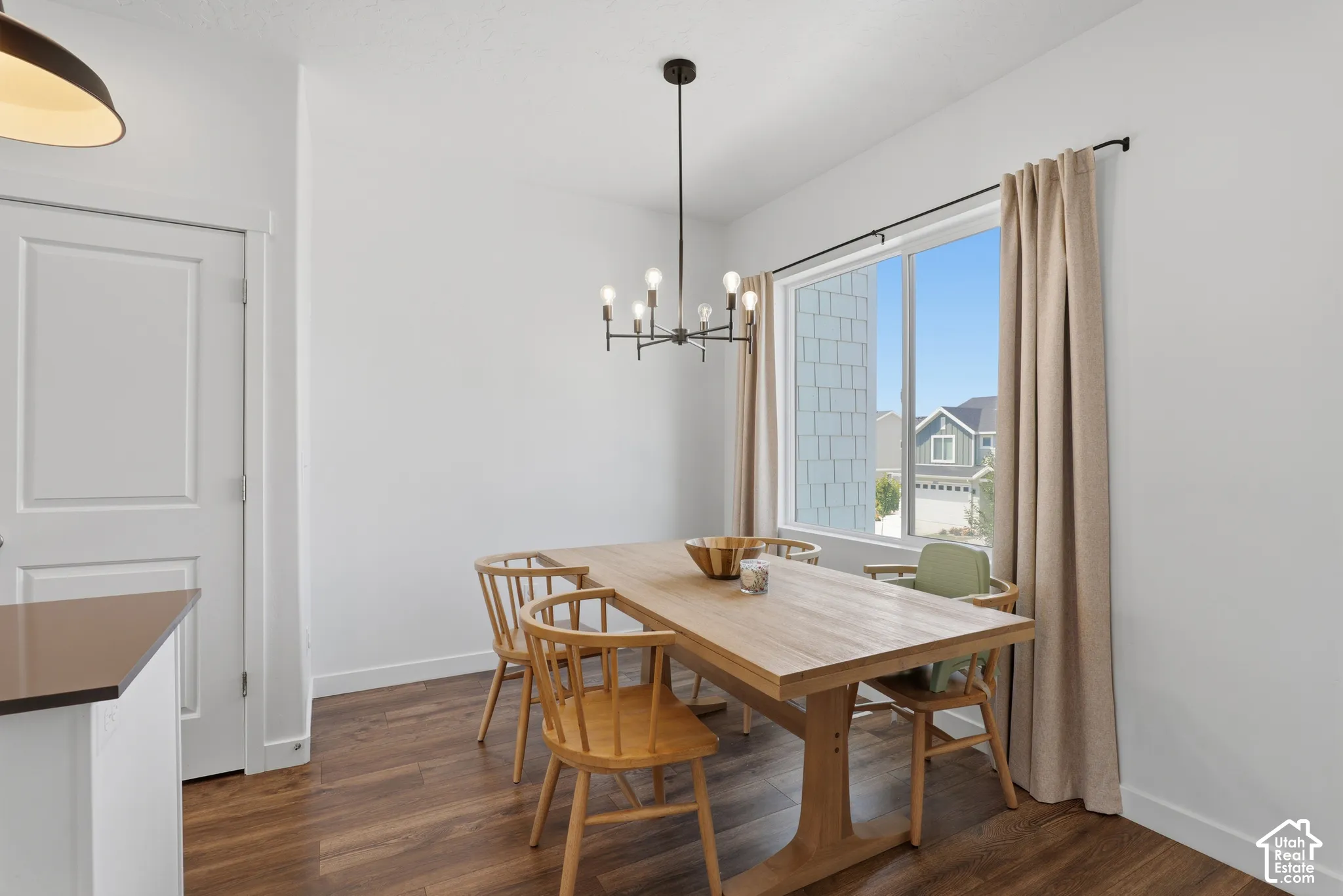 Dining area featuring wood-finish flooring, a large window, and a modern chandelier