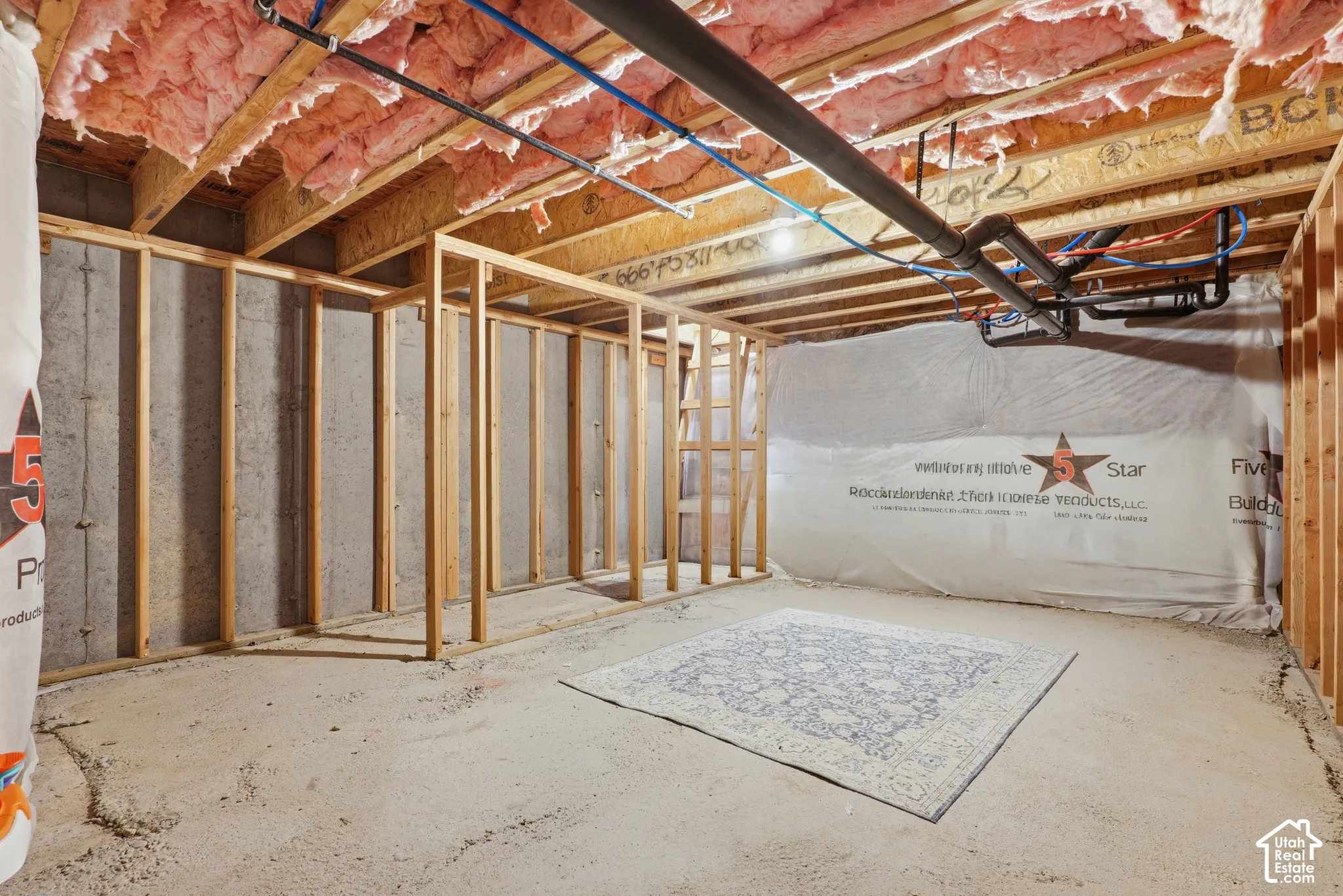 Unfinished basement with concrete flooring, exposed wood framing, and ceiling insulation