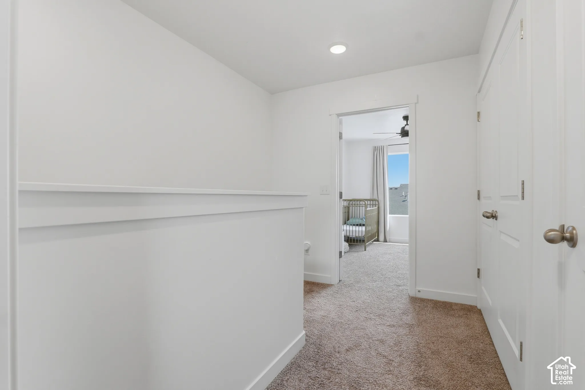 Carpeted hallway featuring white walls, recessed lighting, and white paneled doors with bronze-finish hardware