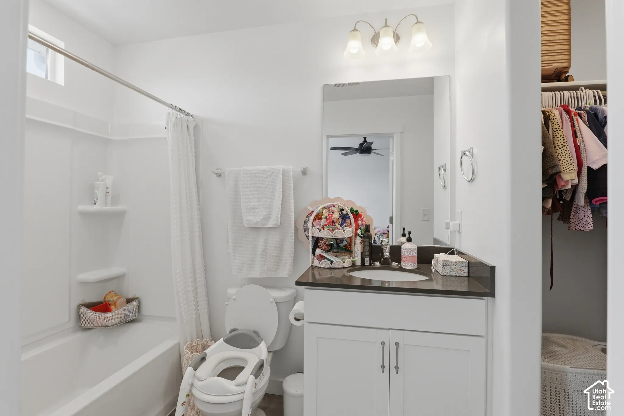 Bright, updated bathroom featuring a white vanity with dual-sink configuration, dark countertop surface, and chrome fixtures