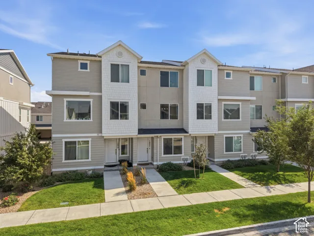 Multi-level townhome featuring a neutral-toned exterior, gabled roof accents, and multiple windows