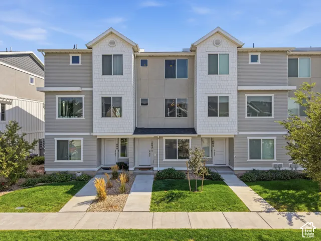 Three-story exterior featuring multi-toned siding, gabled roof accents, and concrete pedestrian pathways with landscaped borders