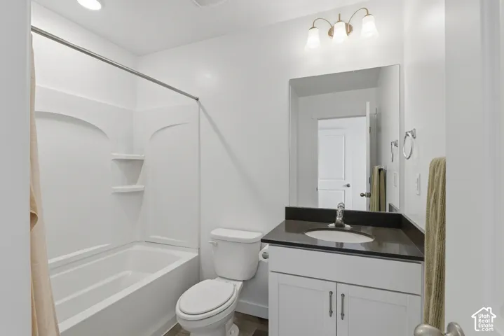 White vanity with dual-door cabinetry, dark countertop, and integrated sink