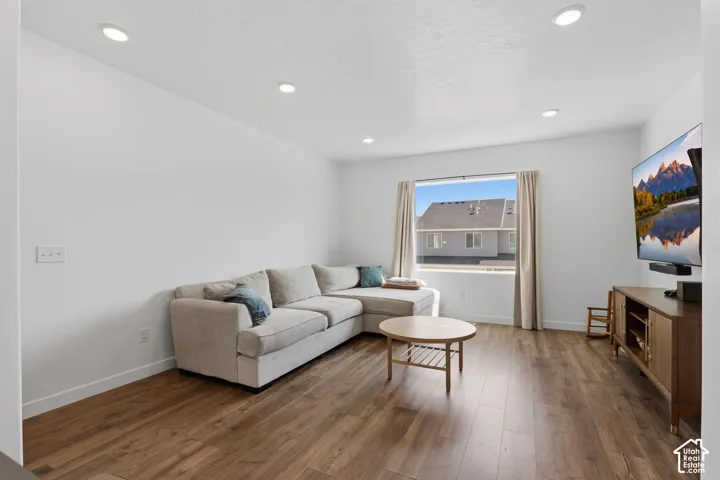 Recessed lighting illuminates this bright interior featuring wood-finish flooring and a window with light-filtering drapes