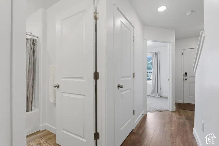Hallway featuring wood-finish flooring, white paneled doors, and recessed lighting