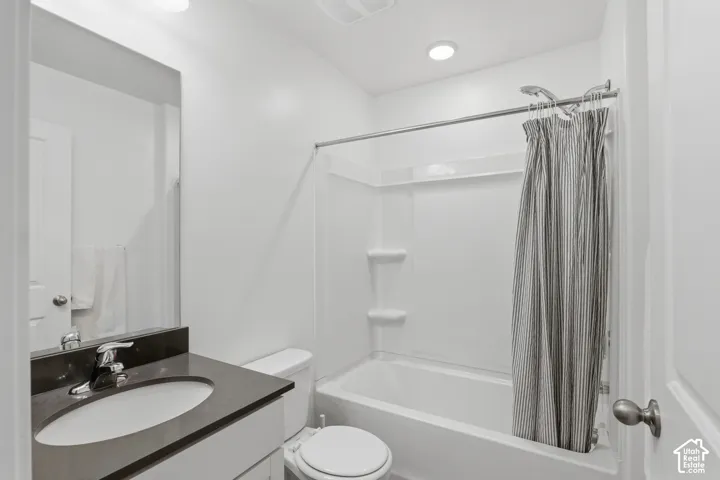 Bathroom featuring a white vanity with a dark countertop, an undermount sink, a chrome faucet, and a shower-over-tub combination with a white surround