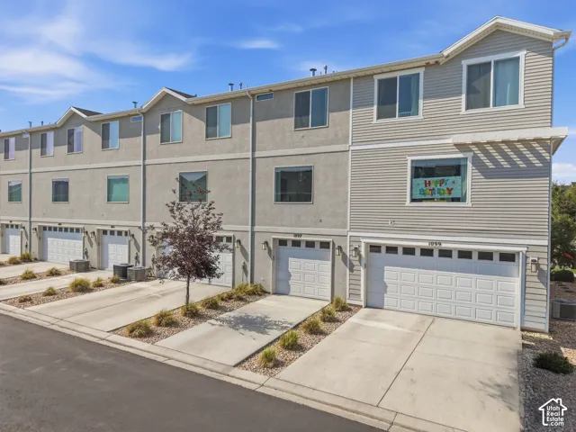 Townhome exterior featuring varied siding materials, attached garages with individual driveways, and multiple windows