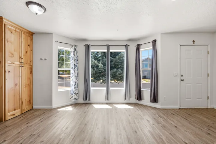 Bright, open living space showcasing wood-finish flooring, multiple glass sliding doors with natural light exposure, and white six-panel doors
