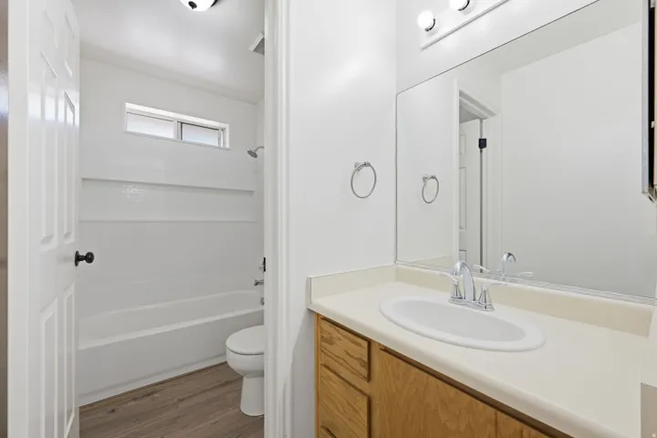 White bathroom featuring a single vanity, integrated sink, and wood-finish cabinetry