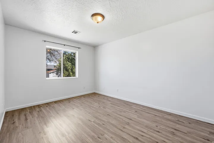 Neutral wall color, wood-finish flooring, ceiling-mounted light fixture, and a window with exterior visibility
