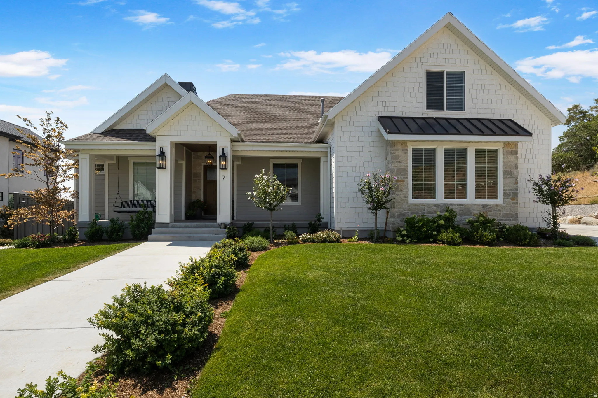 Craftsman-style exterior with a covered porch, stone accents, shingle siding, and a gabled roofline