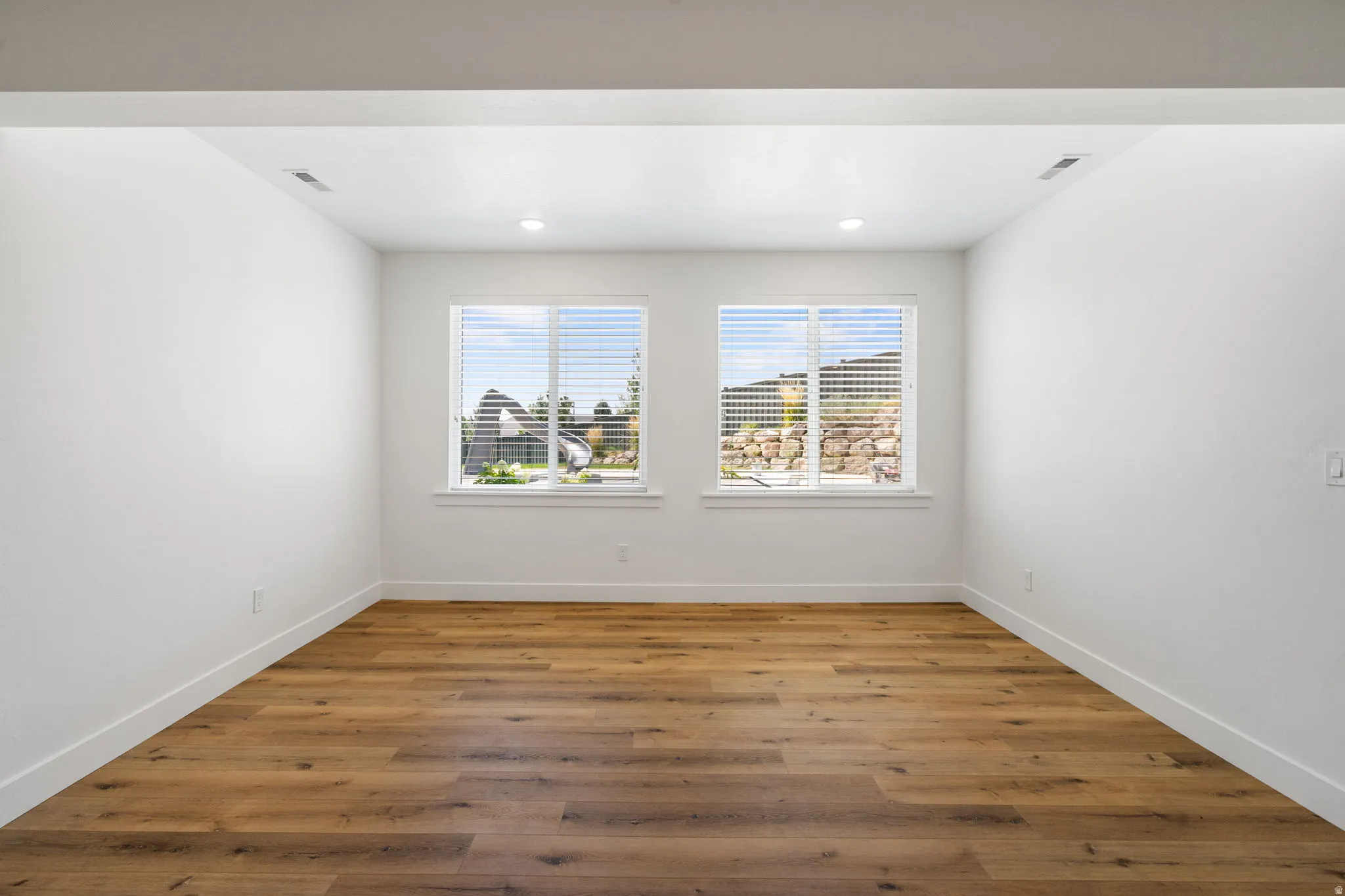 Wood-finish flooring, recessed lighting, and two windows with blinds