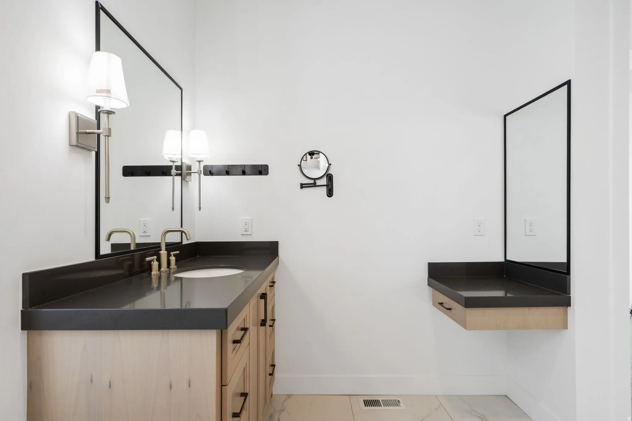 Expansive vanity with a single basin, dark countertop, and wood-finish cabinetry
