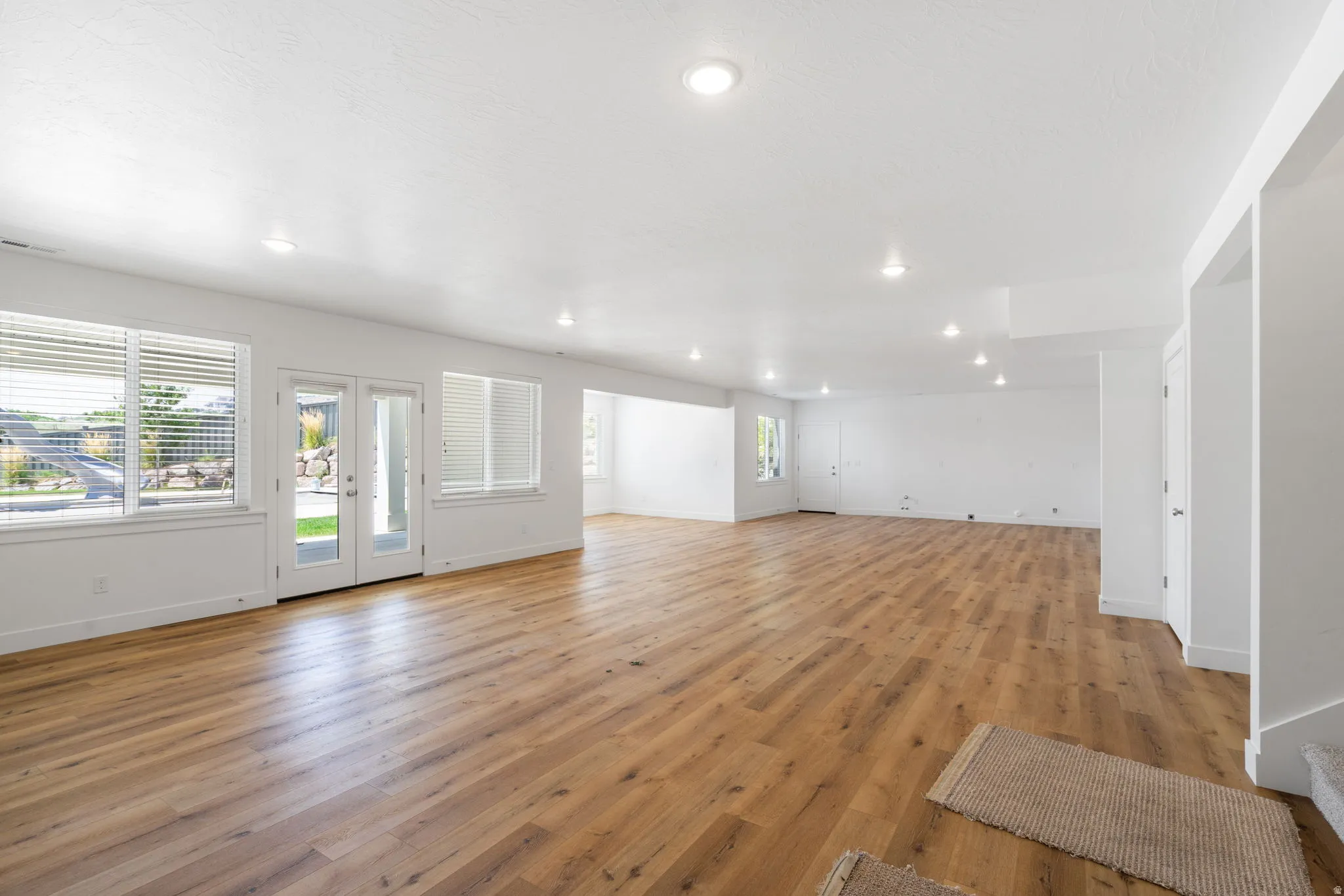 Expansive room with wood-finish flooring, recessed lighting, and white walls