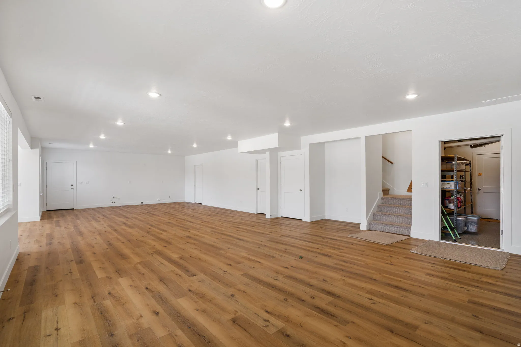 Expansive open-concept room featuring wood-finish flooring, recessed lighting, and crisp white walls