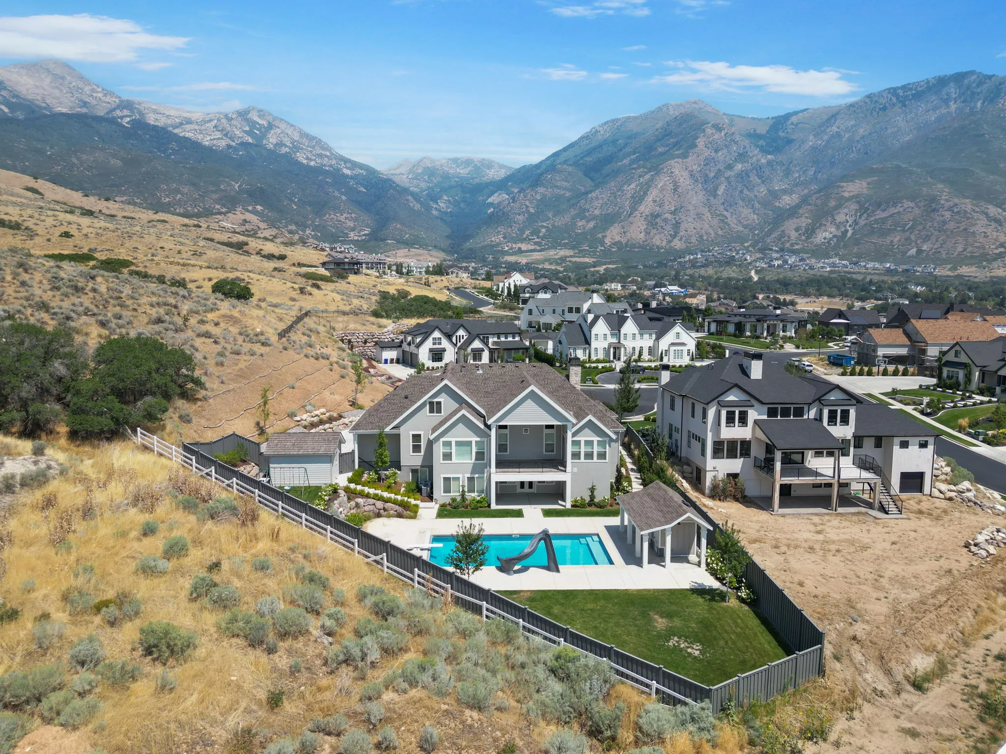 Two-story residence with a gray exterior, a swimming pool, and an adjacent gazebo