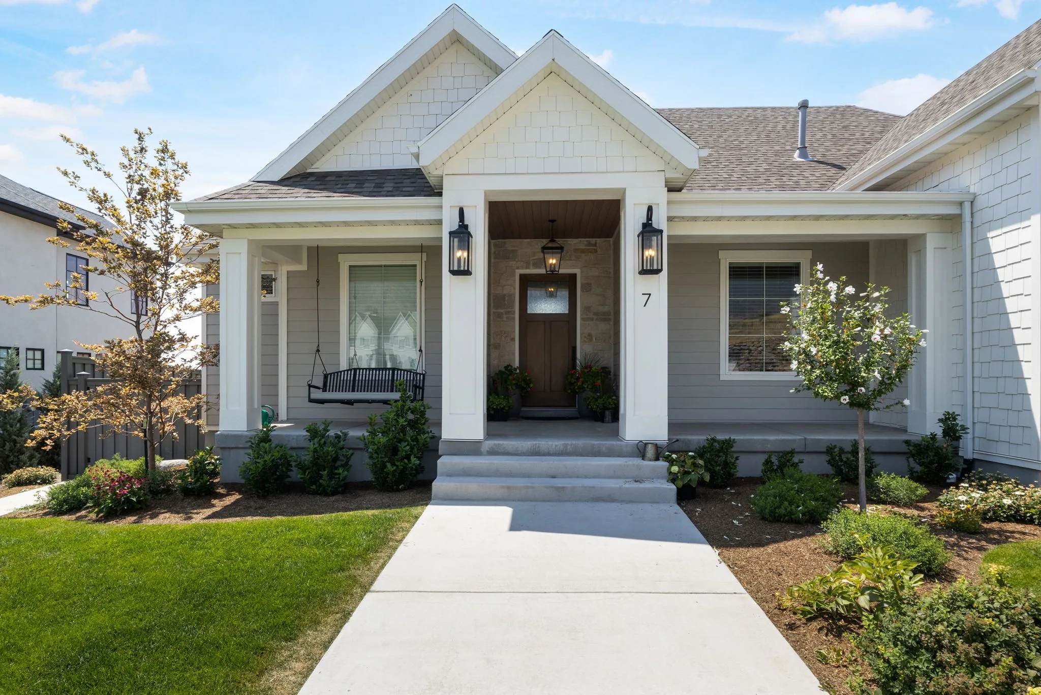 Covered front porch with substantial white columns and stone accents