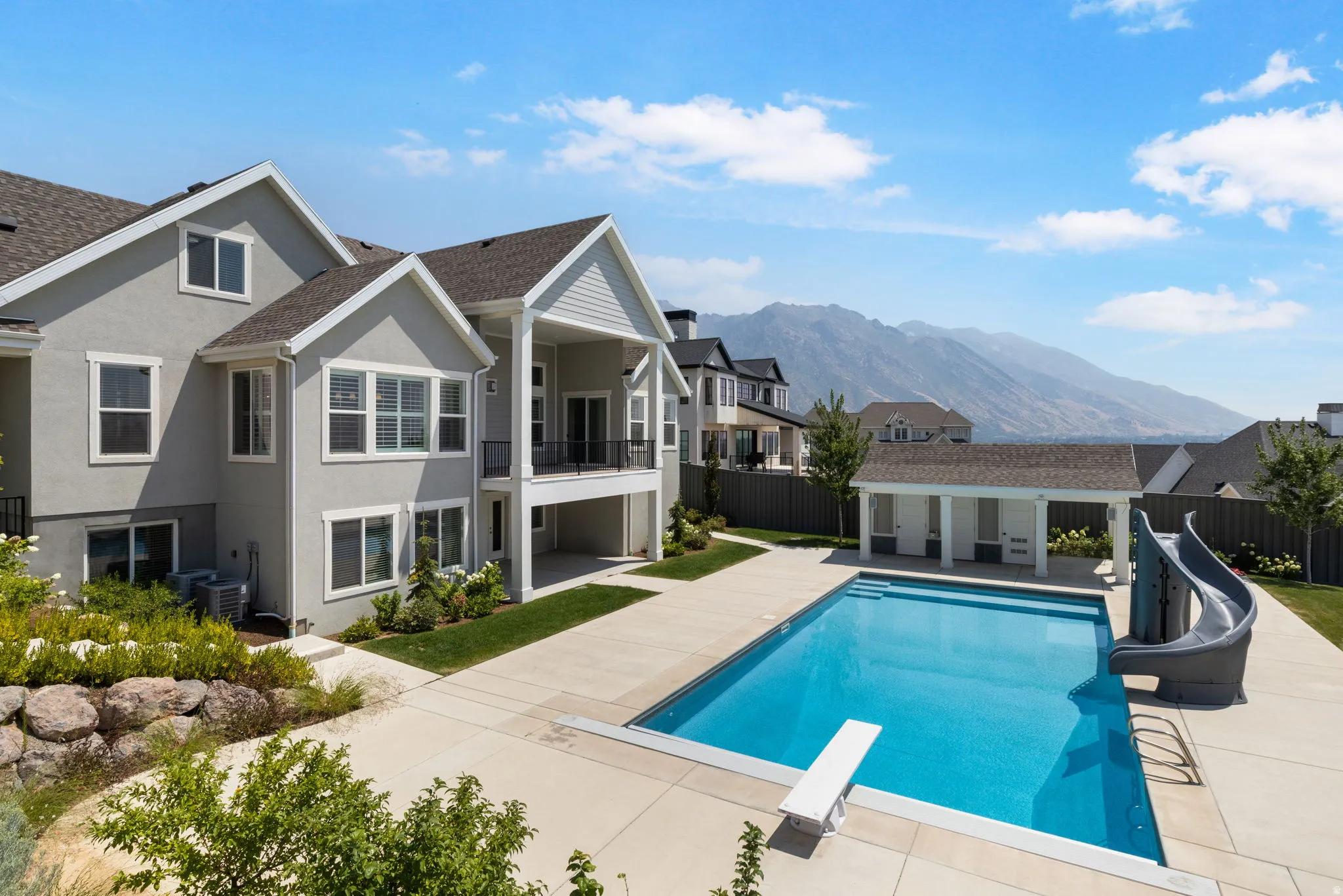 Exterior with a private balcony, a ground-level covered patio, and a backyard swimming pool