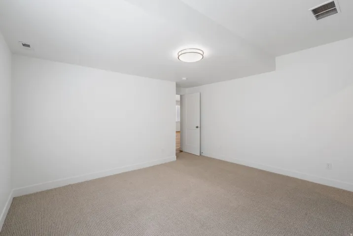 Recessed ceiling light, neutral wall paint, carpet flooring, interior door with chrome hardware, and white trim