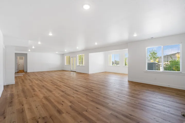 Expansive open-concept living area featuring wood-finish flooring, recessed lighting, and multiple windows
