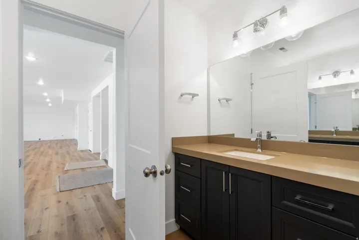 Bathroom vanity with a rectangular undermount sink, a wide mirror, and a three-light fixture