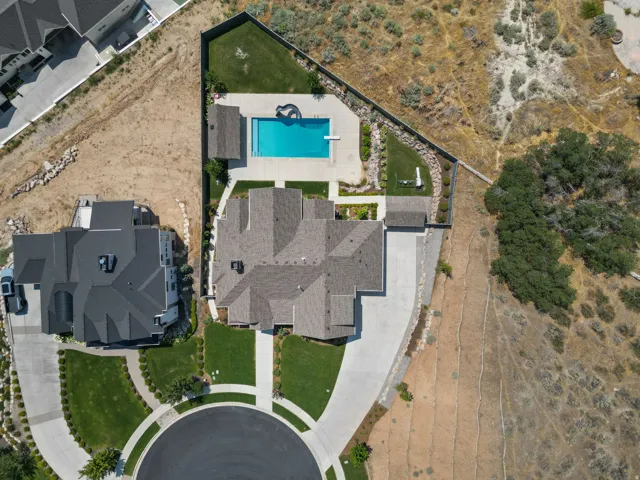 Expansive property featuring a large swimming pool, paved pool deck, manicured lawn areas, a substantial driveway, and a cul-de-sac street entrance