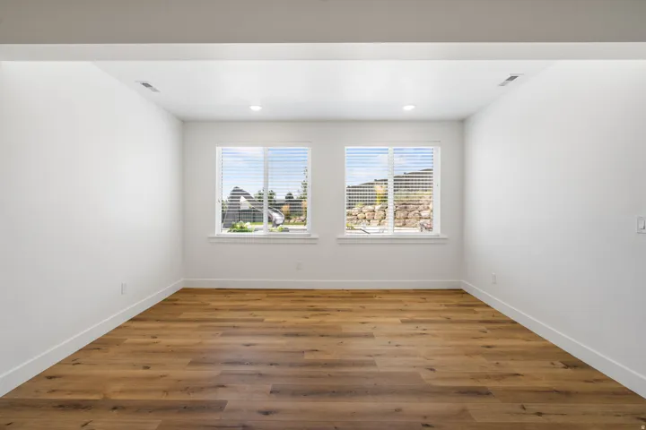 Wood-finish flooring, recessed lighting, and two windows with blinds