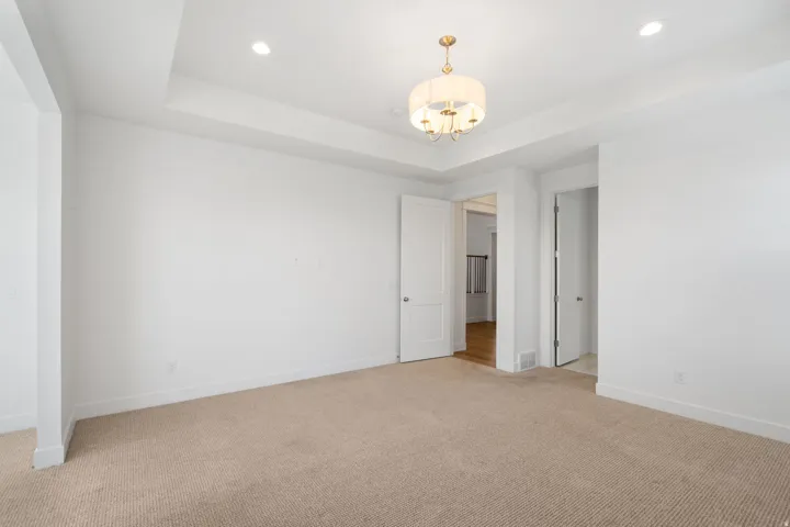 Tray ceiling featuring recessed lighting and a decorative chandelier