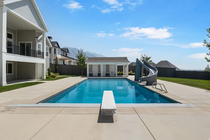 Expansive outdoor area featuring an in-ground swimming pool, diving board, and pool slide