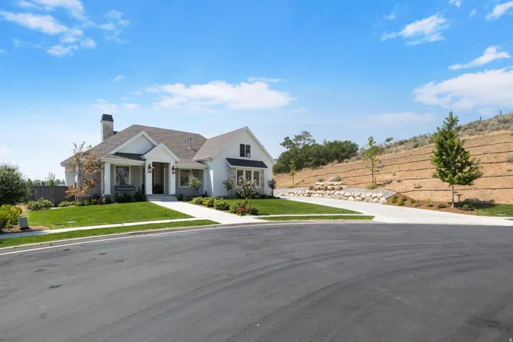Contemporary farmhouse exterior with a covered entry, established landscaping, stone accents, and a concrete driveway