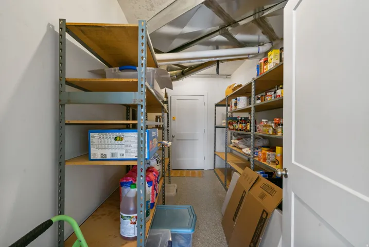 Storage room featuring multiple metal shelving units, a white door, and exposed ductwork