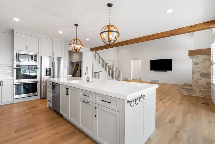 Kitchen featuring white shaker cabinetry, stainless steel appliances, a center island with a white countertop, and wood-finish flooring