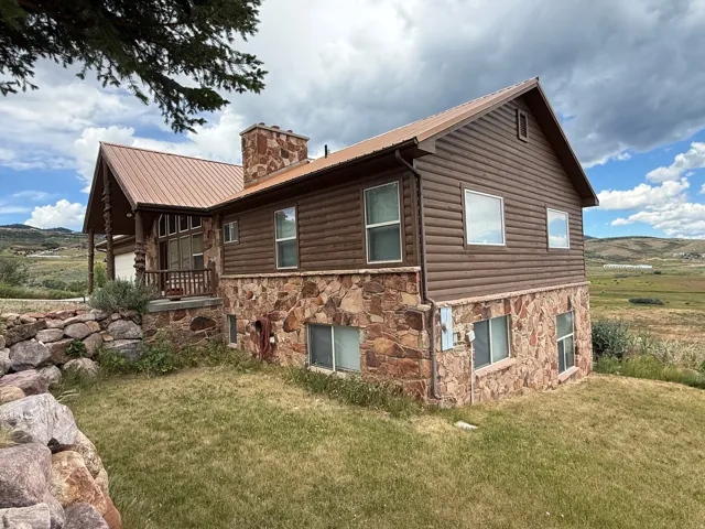 Exterior featuring covered porch, log siding and stone accents