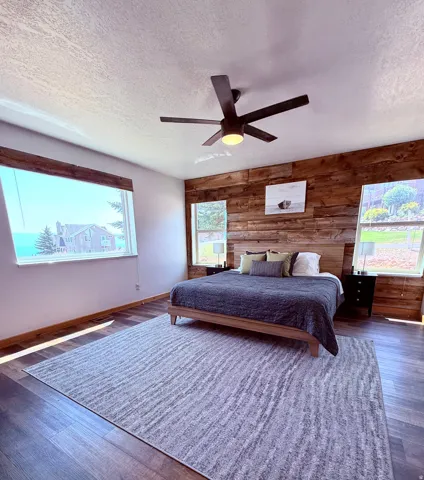 Spacious room featuring expansive window offering views of the lake, a wood-finish accent wall, LVP flooring, and multiple windows with blinds