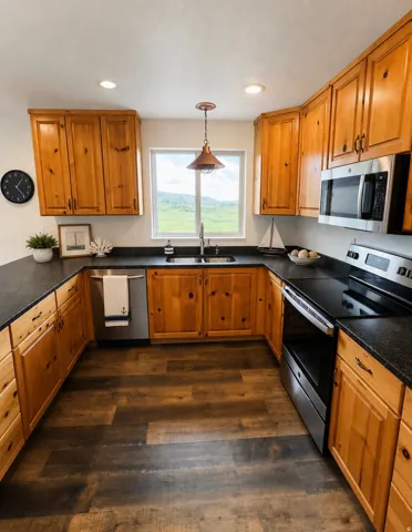 U-shaped kitchen featuring wood cabinetry, dark countertops, wood-finish flooring, and stainless steel appliances