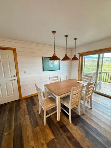 Sweeping views of the farmland, lake views and mountains, LVP flooring, shiplap accent wall, three pendant light fixtures, and a sliding glass door with exterior deck access