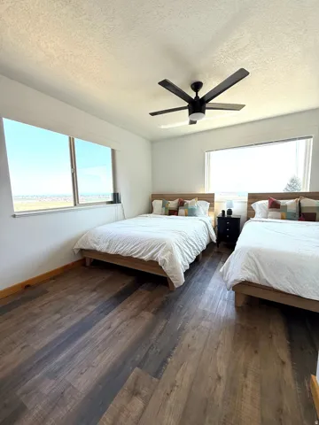 Spacious room featuring large windows with lake views, blinds, LVP flooring, white walls, and a modern ceiling fan with integrated lighting