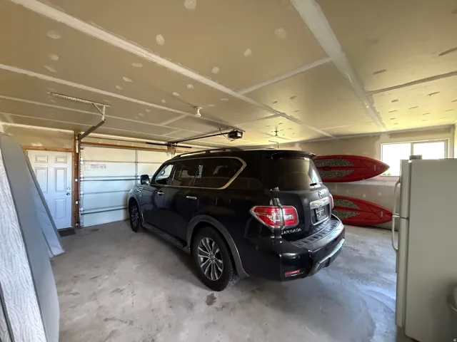 Attached oversized 2-car garage with an overhead door, concrete flooring, and 2 windows
