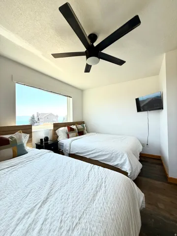 Room featuring a wide window with lake views, blinds, LVP flooring, white walls, and ceiling fan with an integrated light