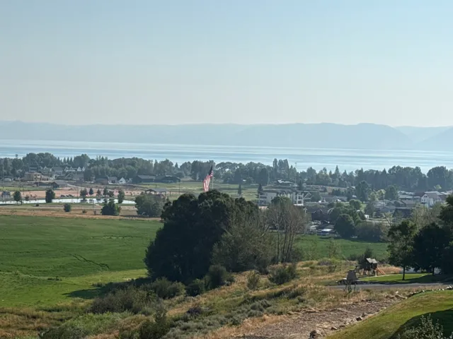 Scenic pastoral setting featuring Bear Lake views, expansive green fields and mature tree clusters