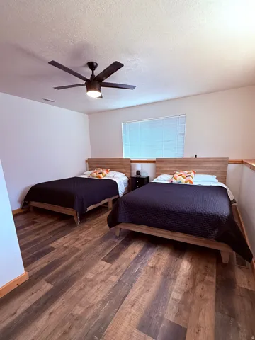 Bedroom featuring LVP flooring, a ceiling fan with integrated lighting, and two large windows with blinds